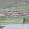 Tibetan houses made of logs and earthen walls along a river.