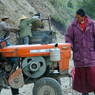 A monk observing a road worker fixing a tractor.