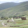 A stupa and several Tibetan houses near a stream.