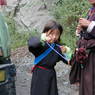 A young Tibetan girl wearing a black chuba and holding a rosary.