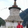 A Tibetan monk standing in front of the large stupa at Dudo.