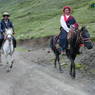 A couple traveling on horseback.