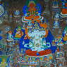 Close-up of buddhas, saints, and prayers carved and painted into a rock face.