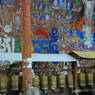 A pilgrim spinning his own prayer wheel as he circumambulates the rock wall's own set of prayer wheels.