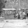 Pilgrims spinning prayer wheels and praying in front of the wall of carvings.