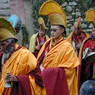Processing yellow hat monks playing cymbals and bells.