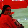 Tibetan women resting under a red umbrella.
