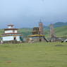 Two smaller square stupas and prayer flag poles across from the county stupa near Larung Gar.