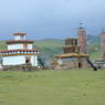 Two smaller square stupas and prayer flag poles across from the county stupa near Larung Gar.