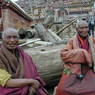 Elderly monks resting on some logs.