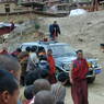 People bowing and greeting Khenpo Jikme Phutsok in the passenger side of the car as he arrives.