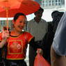 A stylishly dressed Chinese woman with an umbrella and her purchases from the market.