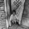 Child, Charikarka village below Lukla, with one of the "auspicious" Tibetan Buddhist on the doorcovering,  Khumbu region, Nepal