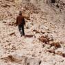 An assistant with measurement tape in hand walking along the terrace created by the retaining wall of the north sector.