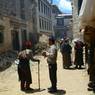 -Pilgrims  walking down prayer wheel lined lane towards rMe ru monastery.