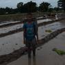 A Boy standing in the wet field with his bamboo basket